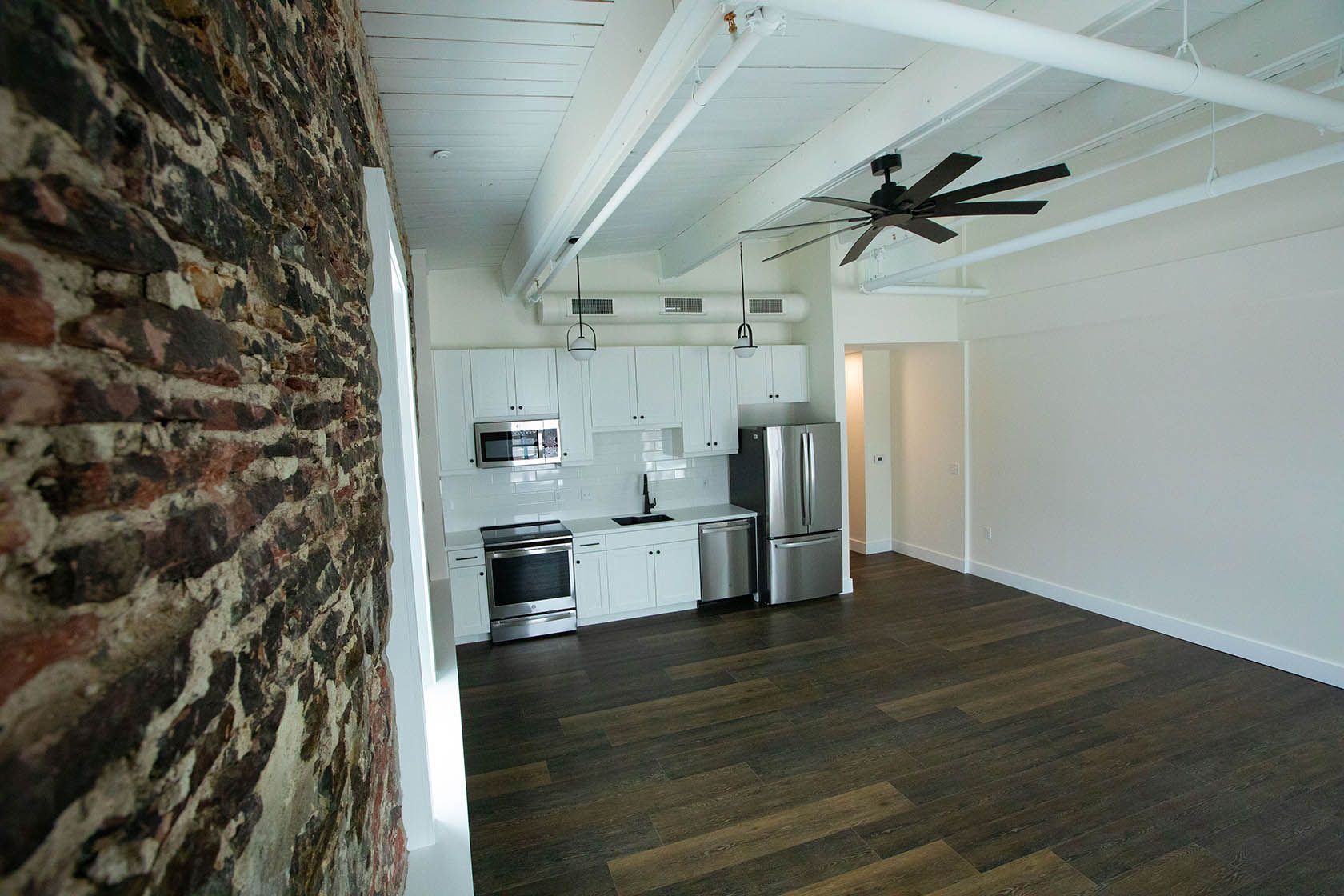 Apartment kitchen with wood counters, stainless appliances, and stone wall